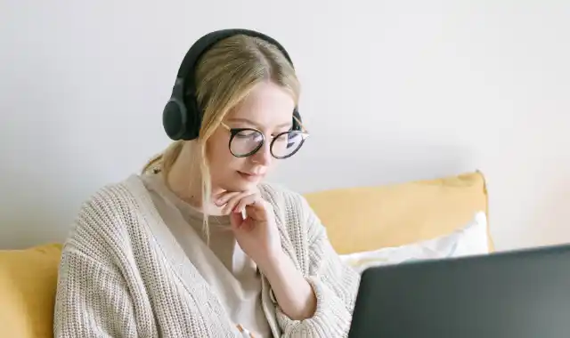 Eine Frau mit Kopfhörern betrachtet einen Laptopbildschirm